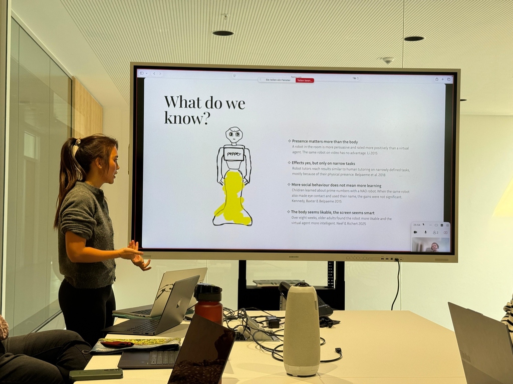 Woman presenting with Pepper robot, screen, and laptop.